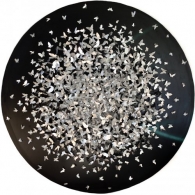 Hand-cut aluminium sheets in various butterfly shapes, glued together forming a circular shape on a black background.