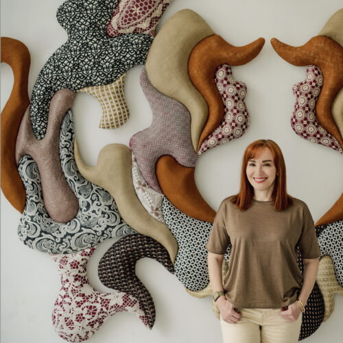 image of artist pavlina vagioni inside her studio with a big wall sculpture in the background