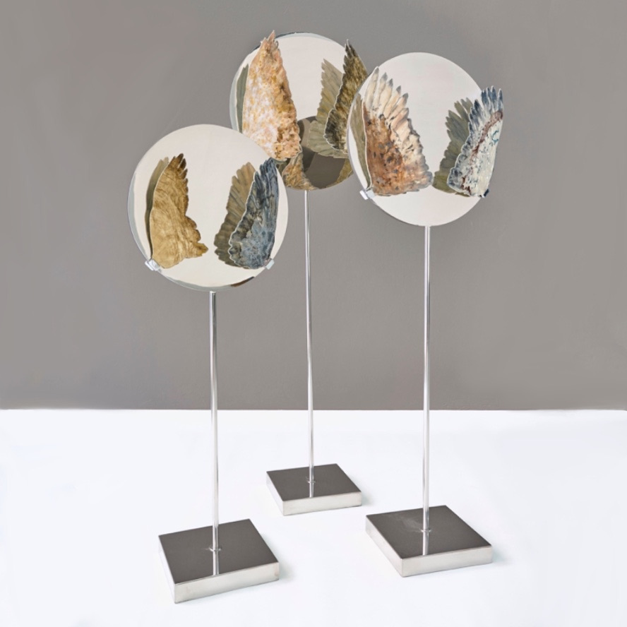three sculptures positioned in a triangle. Round top with bird wings on the sides and mirror reflections.