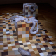 Art installation with large checkered cubes and a silver snakes sculpture weaving around and over the blocks on a multicolored tiled floor.